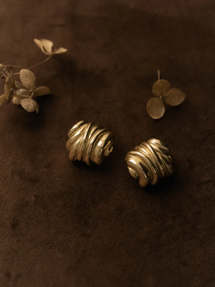 گوشواره‌های طلا کنار گل خشک روی مخمل